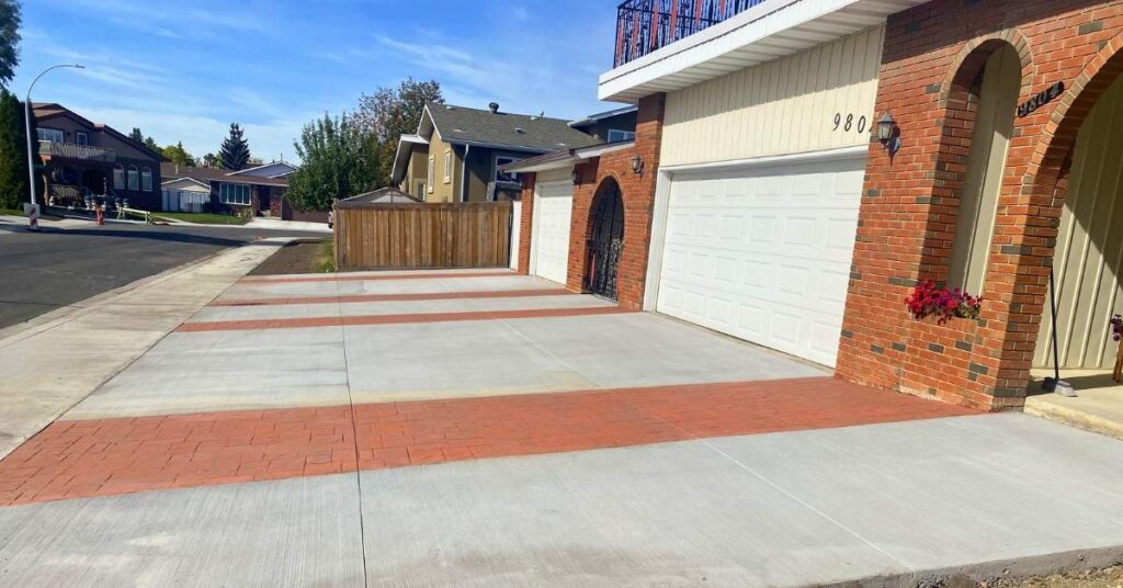 A custom residential concrete driveway in Edmonton featuring decorative terra cotta stamped borders.